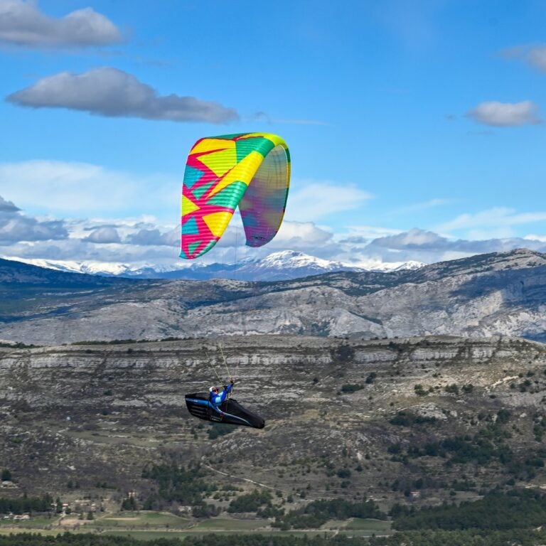 Paraglider over limestone alpine mountains — a flight scene